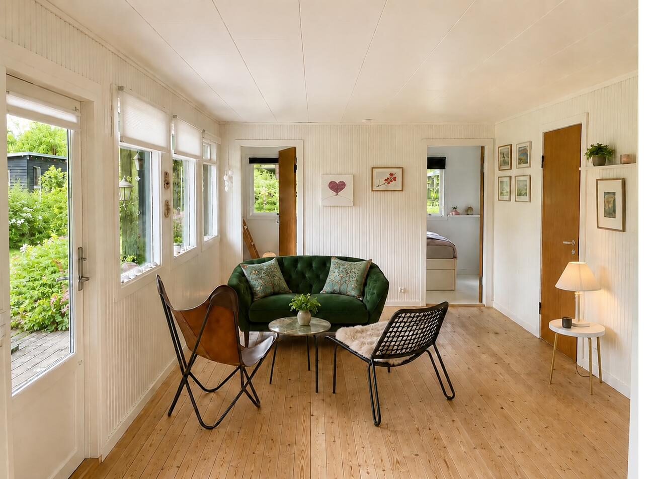 Lys opholdsstue med brændeovn og grøn veloursofa – sommerhus til salg Nordsjælland