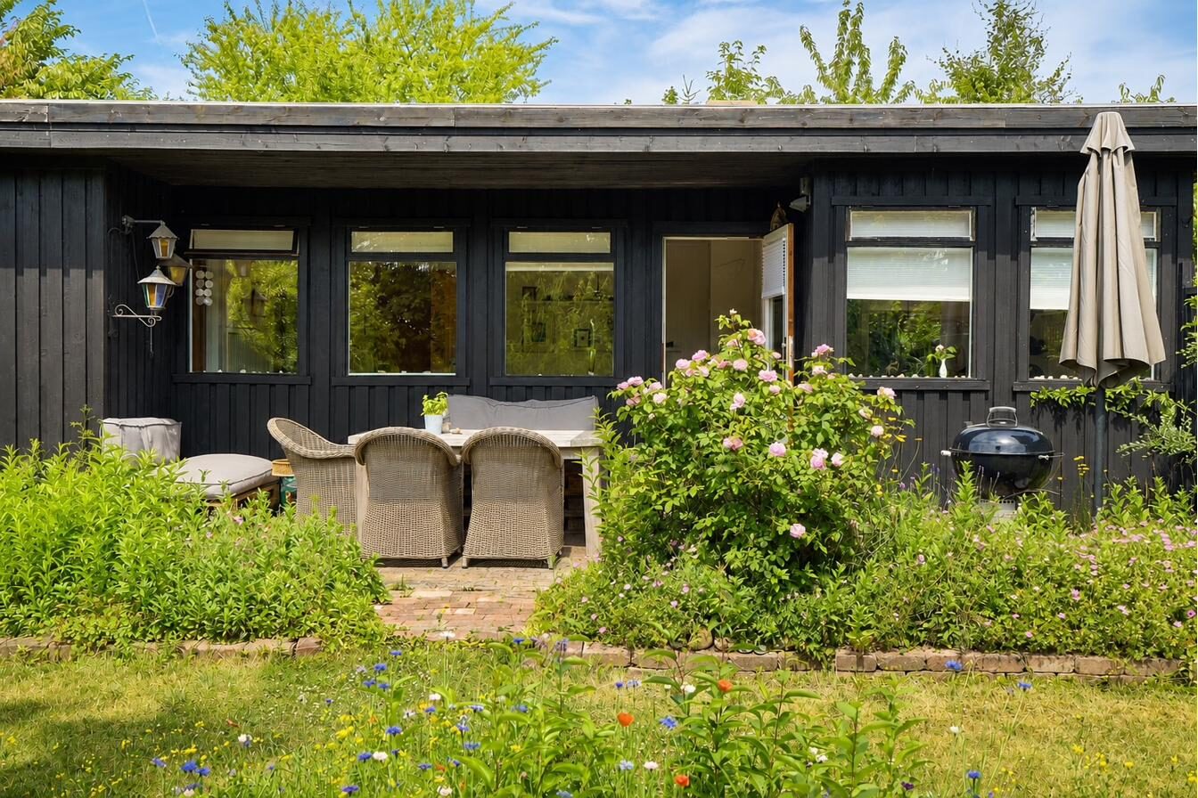 Terrasse med blomstrende roser langs det sorte træhus – Nøddevej 9 til salg